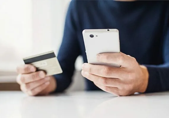 Male hands holding credit card and using smart phone. Online sho